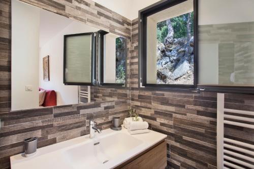 un baño con lavabo y dos espejos en Villa No Stress Aria di Petra, en Olmeto