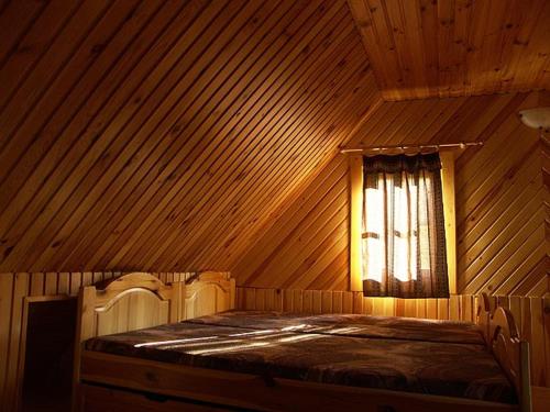 een bed in een houten kamer met een raam bij Dvor Magduška in Osturňa