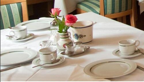 a table with plates and cups and flowers on it at Pension Gletscherblick in Fulpmes