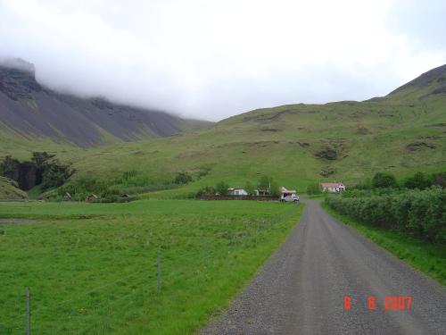 a dirt road in the middle of a green hillside at Ásólfsskáli Cottage in Ásólfsskáli