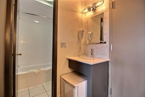 a bathroom with a sink and a mirror and a shower at Hotel Motel Le Quiet in Lac-Mégantic