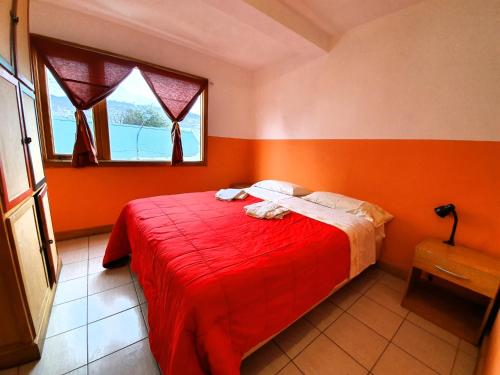 um quarto com paredes cor de laranja e uma cama com um cobertor vermelho em YAGHAN HOSTEL em Ushuaia