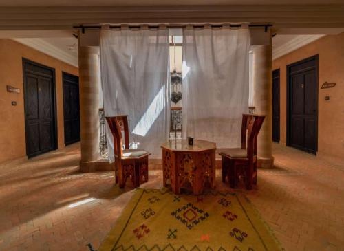 a room with a table and chairs and a curtain at Riad Les Jardins de Tafraoute in Foum Mharech
