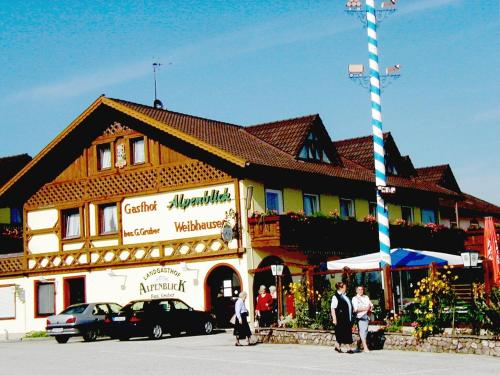 ein großes Gebäude mit Leuten, die draußen stehen in der Unterkunft Alpenblick Weibhausen in Weibhausen