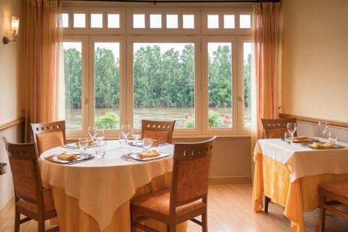 a dining room with two tables and a large window at Hotel Hostellerie De La Gabelle in Saint-Florent-le-Vieil