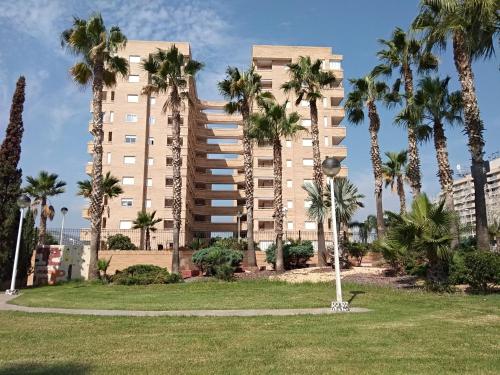 un gran edificio de apartamentos con palmeras en un parque en ACV - Aguamarina-2ª línea, planta 7, norte en Oropesa del Mar