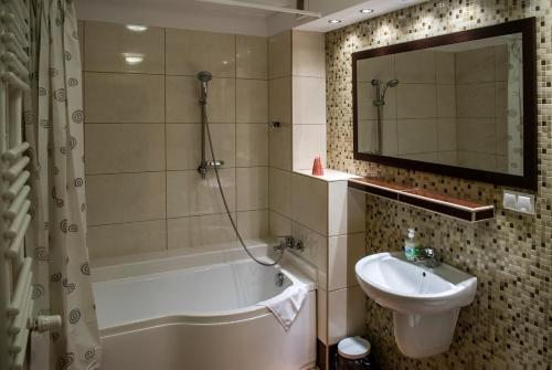 a bathroom with a tub and a sink and a mirror at Hotel Hensch in Łódź