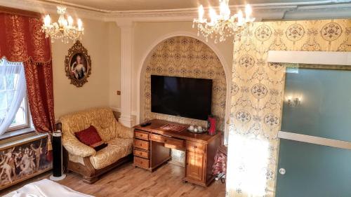 a living room with a tv and a chair and a table at Rezidence Zámeček - Boutique Hotel in Františkovy Lázně