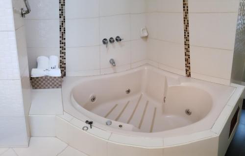 a white bath tub in a white tiled bathroom at Hotel Centenario in Puerto Maldonado