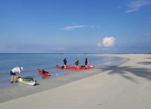 a group of people standing on a beach with boats at Mutiara Beach Resort in Berakit