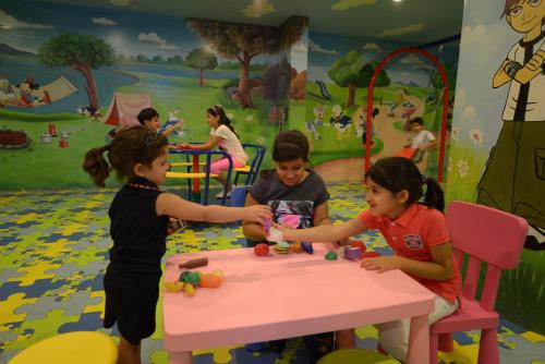 a group of children playing around a pink table at Boudl Al Woroud بودل الورود in Riyadh