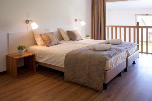 a bedroom with a large bed and a wooden floor at Newhouse Logies in Zevenhoven