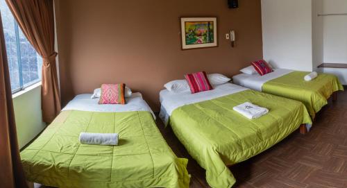 a room with three beds with green sheets at Tupac Lima Airport in Lima