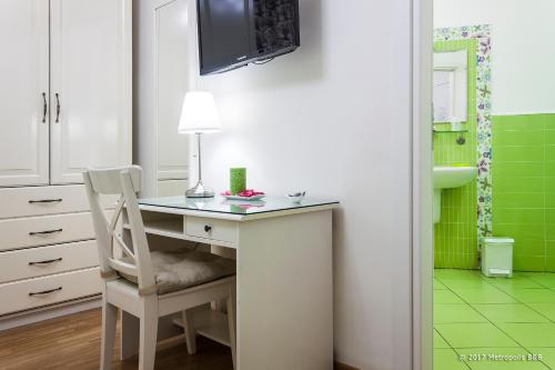 a desk with a chair in a bathroom with green tiles at Metropolis B&B in Messina