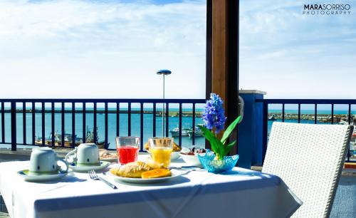 una mesa con comida y bebida y vistas al océano en Hotel Al Faro, en Licata