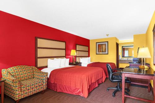 two beds in a hotel room with red walls at Welcome Inn in Milledgeville