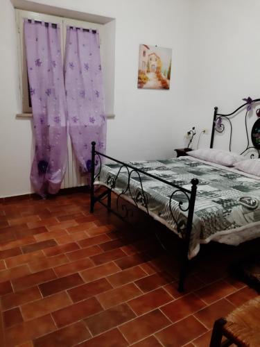 a bedroom with a bed and purple curtains at Agriturismo Uliveto Gretacci in Montemerano