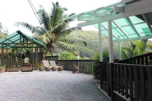 a patio with a fence and chairs and a palm tree at Stephna Residence in Anse Boileau