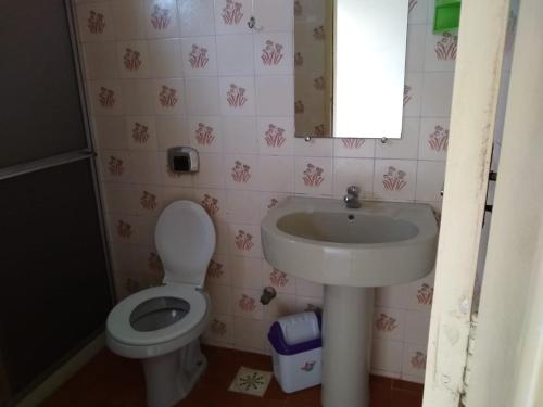 ein Badezimmer mit einem Waschbecken, einem WC und einem Spiegel in der Unterkunft 1 quarto 2 camas de solteiro in Guarapari