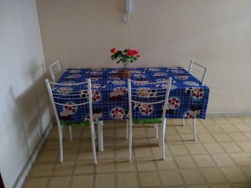 einen Tisch mit einem blauen Tischtuch mit einer Blumenvase darauf in der Unterkunft 1 quarto 2 camas de solteiro in Guarapari