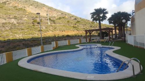 a large swimming pool with a hill in the background at Cabo de Palos apartamento vacacional in Cabo de Palos