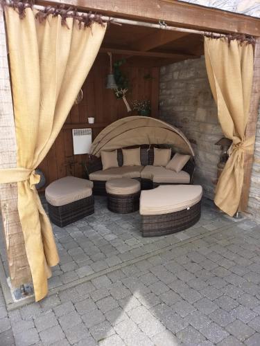 un patio coperto con un letto e 2 posti a sedere in vimini di La petite suisse a Malmedy
