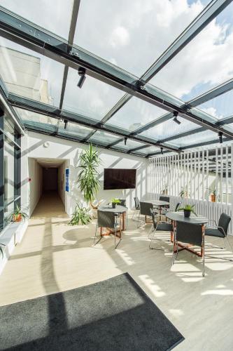a glass roofed patio with tables and chairs at Zaliakalnio terasos apartamentai in Kaunas