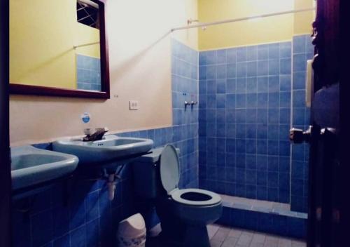 a blue tiled bathroom with a toilet and a sink at La Merced Plaza Hospedaje in Riobamba