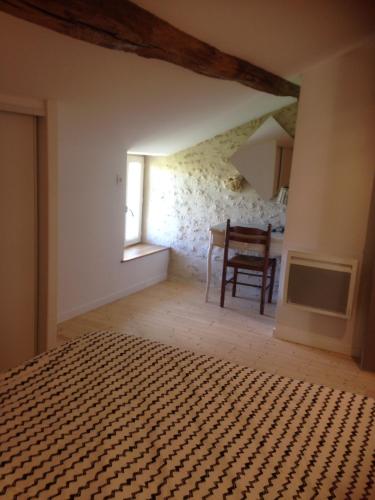 une chambre avec un lit, une table et une fenêtre dans l'établissement Le puit du lavoir, à Thiré