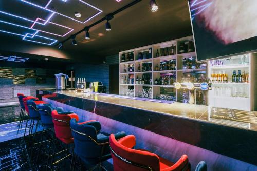 a bar with red and blue chairs in a room at Beluga Hotel in Atyraū
