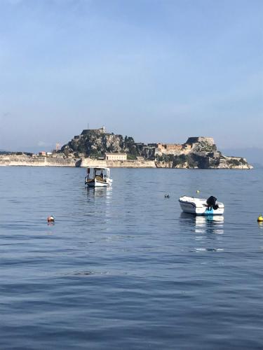 two boats in the water with an island in the background at Eros Beach Hotel in Benitses