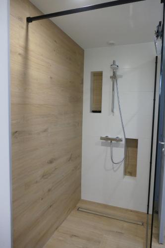 een douche in een badkamer met een houten muur bij La Loge Bertine in Saint-Mars-la-Réorthe