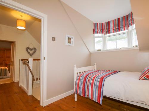 a white bedroom with a bed and a window at 61 Seatown in Buckie
