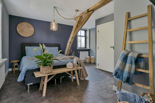sypialnia z niebieskimi ścianami i łóżkiem ze stołem w obiekcie Logement 1818 w mieście Bakel