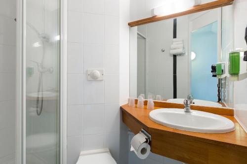 y baño con lavabo y ducha. en HOTEL EDEN - Metz Nord, en Woippy