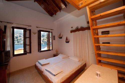 a bedroom with a bed and two windows at Odyssia in Symi