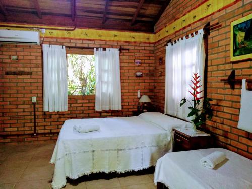 a bedroom with two beds and a brick wall at Morada Crisálida in Praia do Rosa