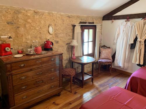 ein Schlafzimmer mit einer Kommode, einem Tisch und einem Fenster in der Unterkunft Ferme de Tayac - Charme avec Pool in Les Eyzies-de-Tayac