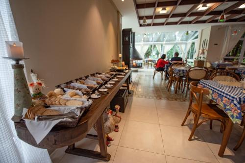 een lang buffet met brood en zoete deegwaren bij Pousada Annecy - Fácil acesso ao centrinho e Baden Bar in Campos do Jordão