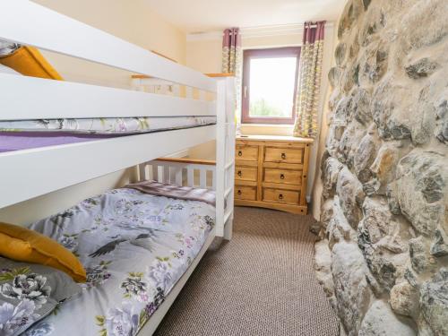 1 dormitorio con literas y pared de piedra en Melin Bach, en Llanfihangel-y-pennant