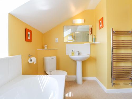 a bathroom with a sink and a toilet and a mirror at Grooms Cottage in Leicester