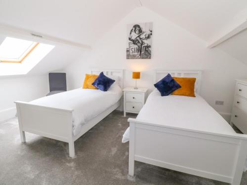 two white beds in a room with a window at Lyngaran House in Holyhead