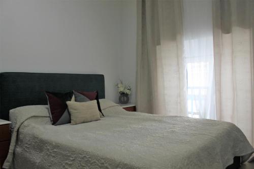 ein Schlafzimmer mit einem großen Bett und einem Fenster in der Unterkunft Apart Baía do Sado I in Setúbal