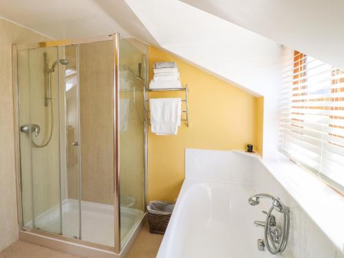a bathroom with a shower and a bath tub at Grooms Cottage in Leicester
