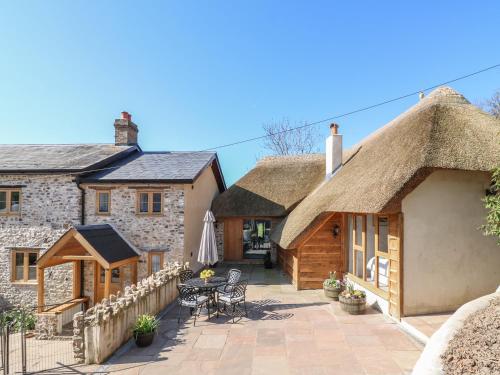 a house with a thatched roof and a patio at The Old Smithy in Honiton