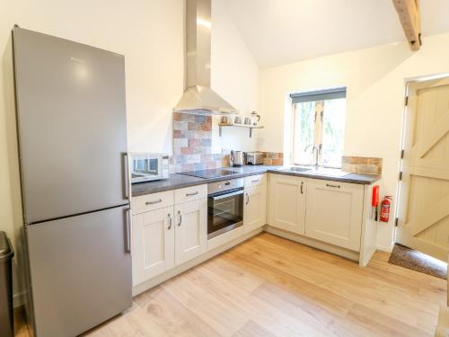 a kitchen with white cabinets and a refrigerator at The Stables in East Dereham