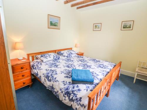 a bedroom with a bed with a blue pillow on it at Poldowrian Farmhouse in Helston