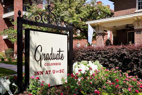 a sign in front of a house with flowers at Graduate by Hilton Columbia SC in Columbia