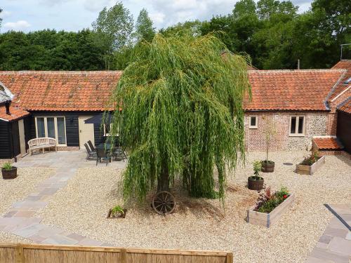a garden with a willow tree in front of a house at The Stables in East Dereham