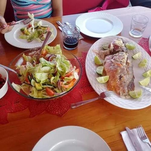 a table with two plates of food and a salad at San Blas Islands - Private Cabin Over-the-Ocean including Meals in Mandinga